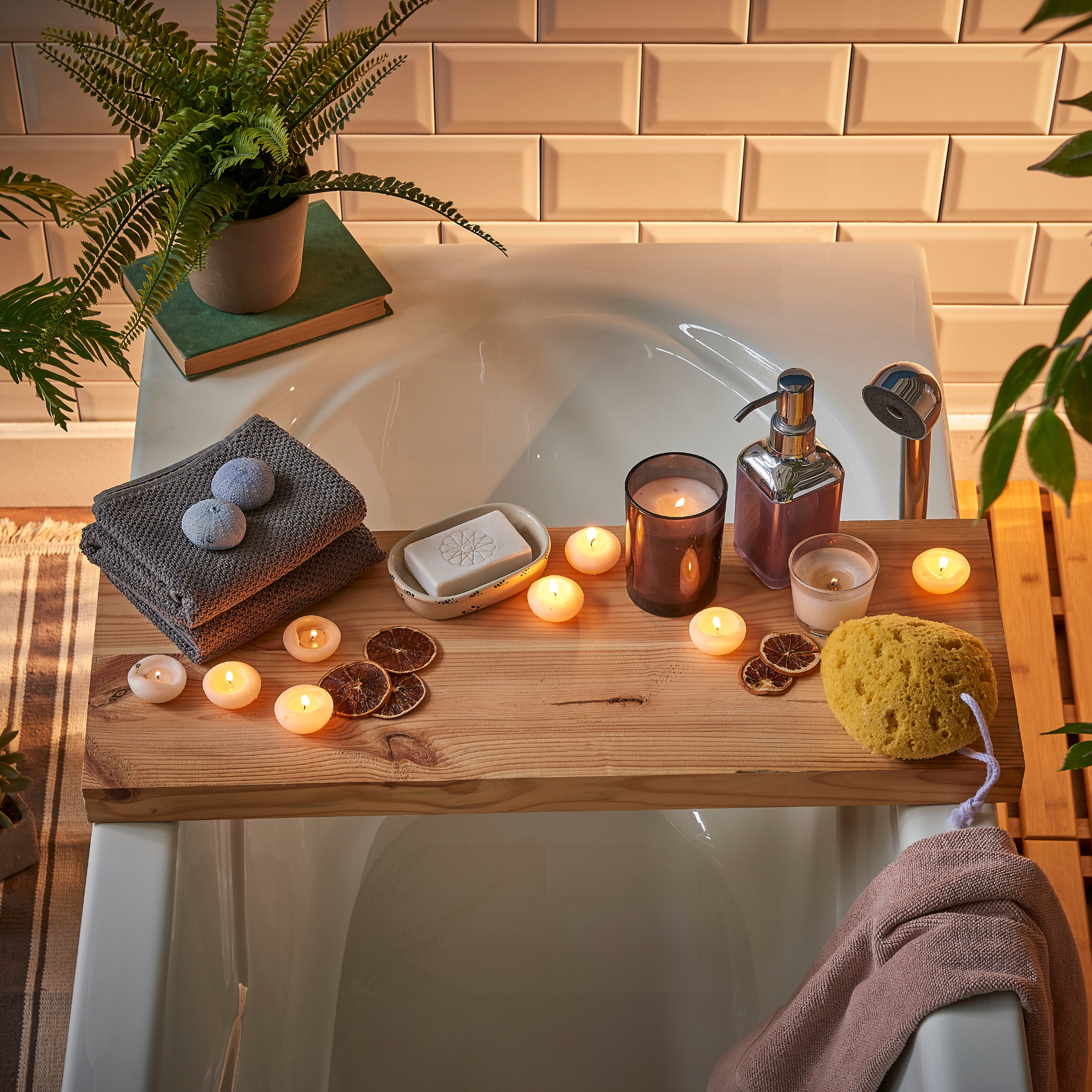 Bathroom setting with a bathtub, wooden tray, candles, and bath items.