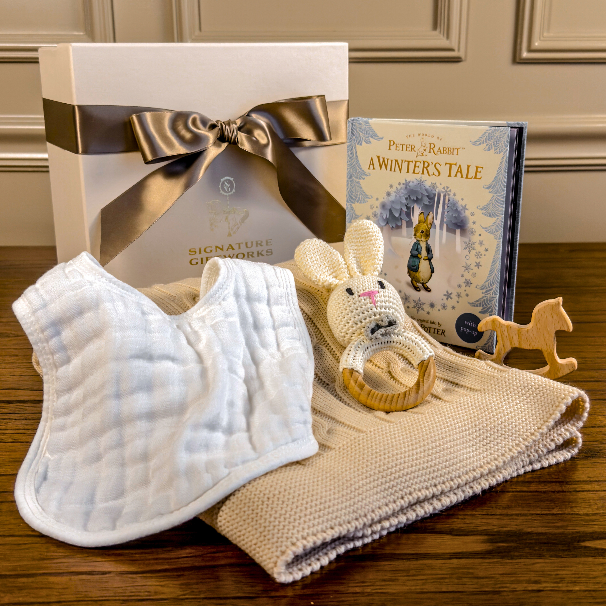 Winter Arrival baby gift set with crocheted bunny rattle, winter storybook, knit blanket, and neutral newborn essentials in a premium gift box.”